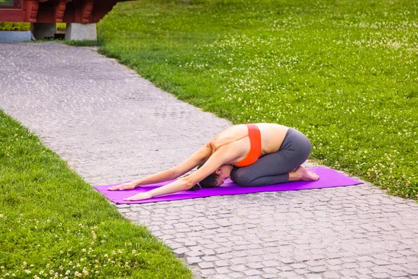 Mladá žena cvičí jógu v parku. — Stock fotografie