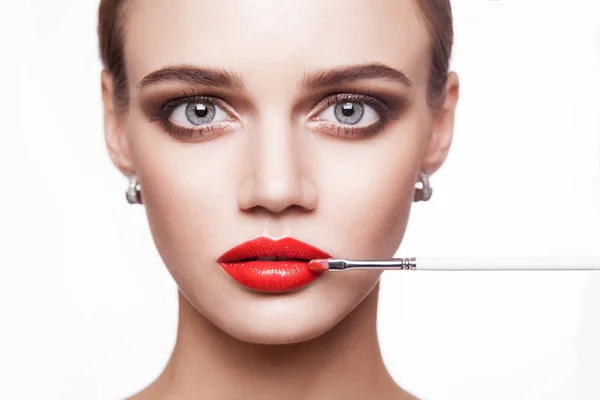 Professionele make-up artiest geldt make-up voor mooie jonge vrouw met blauwe ogen en licht bruin haarstijl en perfecte huid. — Stockfoto