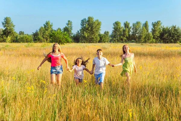 Чотири щасливі красиві діти бігають, граючи разом у прекрасний літній день. стрибає і дивиться на камеру з щастям і зубною посмішкою . — стокове фото