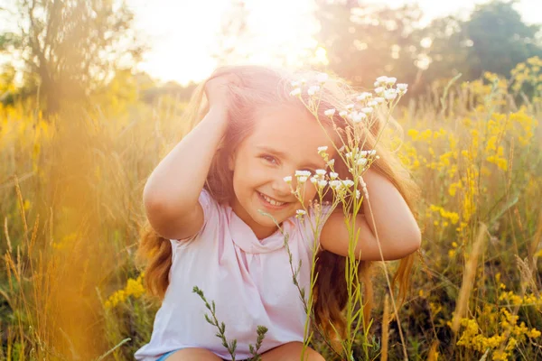 Hermosa niña con el pelo largo y sonrisa en el verano en el parque de la puesta del sol. posando y mirando a la cámara y sonriendo . —  Fotos de Stock