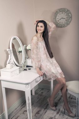 Pembe elbise ve uzun siyah saçları onun odasına partiden önce poz onun tuvalet Masası yakınındaki güzel mutlu kadınla.