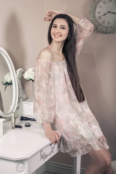 美丽幸福的女人，与粉红色的裙子和黑色的长头发，在她的房间附近聚会前摆姿势她梳妆台. — 图库照片