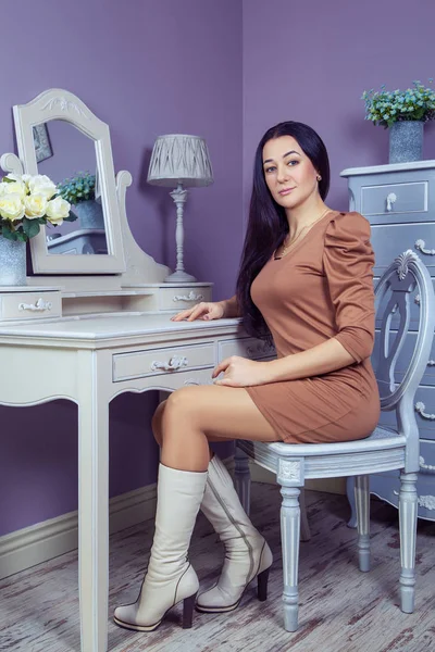 Kahverengi elbise ve uzun siyah saçları onun odasına partiden önce poz onun tuvalet Masası yakınındaki güzel kadınla.