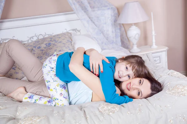 Feliz madre e hija yacen en la cama y se divierten . — Foto de Stock