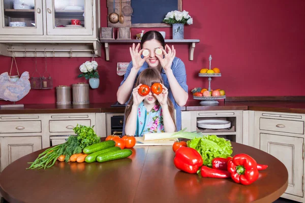 Happy mother and daughter enjoy making and having healthy meal together at their kitchen. they are making vegetable salad and having fun together. mom take care of her daughter and tech how to cook. — Stock Photo, Image
