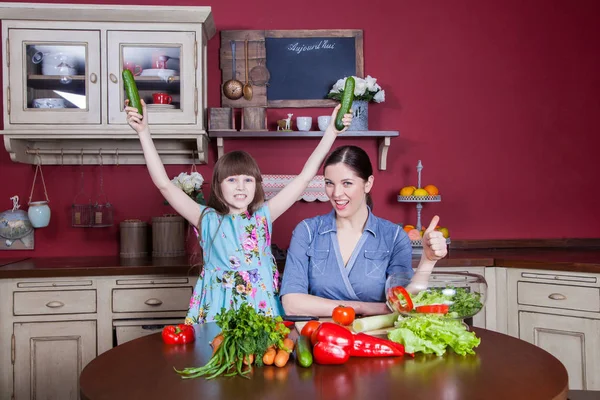 Happy mother and daughter enjoy making and having healthy meal together at their kitchen. they are making vegetable salad and having fun together. mom take care of her daughter and tech how to cook. — Stock Photo, Image