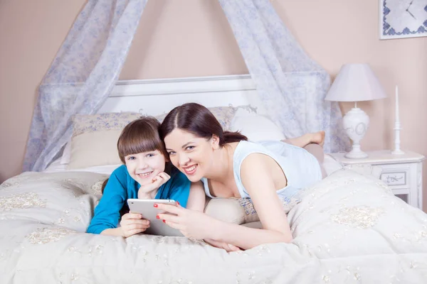 Счастливая мать и дочь лежали в постели с цифровым планшетом . — стоковое фото
