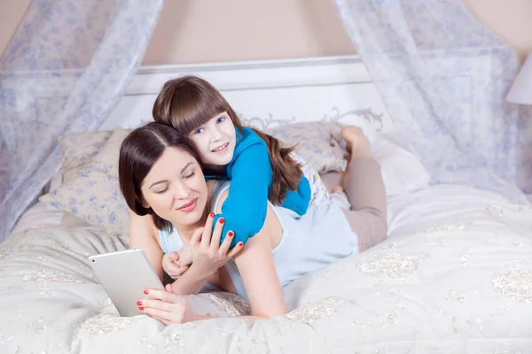 Счастливая мать и дочь лежали в постели с цифровым планшетом . — стоковое фото
