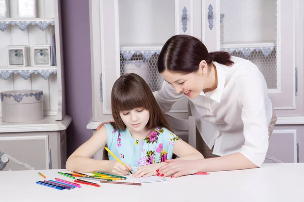 Madre feliz enseña a su hija a pintar . — Foto de Stock