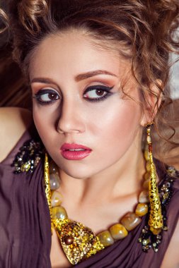 Uzun elbise ve kıvırcık saç modeli ve duvar ahşap kutup ile yakın poz makyaj moda model. Stüdyo vurdu. 