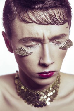 Yüksek moda güzellik altın genç modelinin delici takı ve makyaj kanatlar. Stüdyo vurdu.