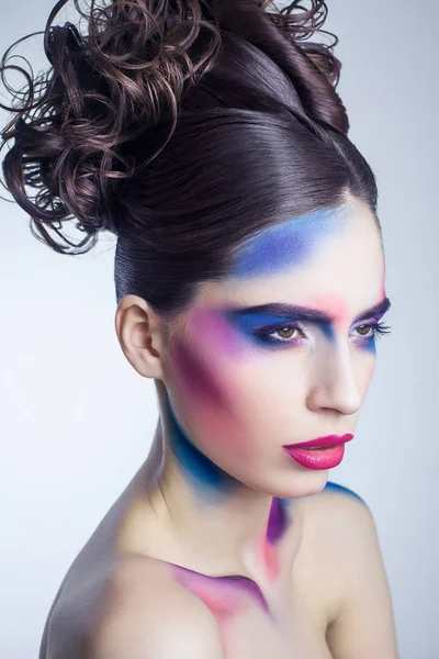 Krásná mladá žena s kreativní barevný make-up a kudrnaté shromažďovány účes a maloval barevné tělo. — Stock fotografie