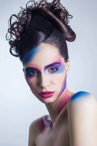 Hermosa mujer joven con maquillaje de color creativo y rizado recogido peinado y pintado cuerpo de color . —  Fotos de Stock