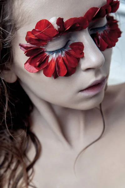 Retrato de belleza de la joven modelo de moda con pelos húmedos y pétalos de flores rojas alrededor de sus ojos. estudio de tiro sobre fondo azul —  Fotos de Stock