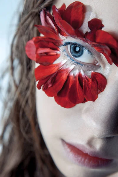 Retrato de belleza de la joven modelo de moda con pelos húmedos y pétalos de flores rojas alrededor de sus ojos. estudio de tiro sobre fondo azul —  Fotos de Stock