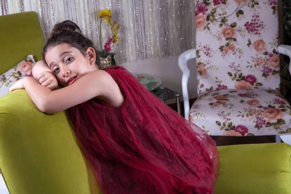 Roztomilý lovlely Středního východu dívka s tmavě červené šaty a vlasy pózuje a liying shromážděny na zelené sofa na domácí interiér. Studio záběr — Stock fotografie