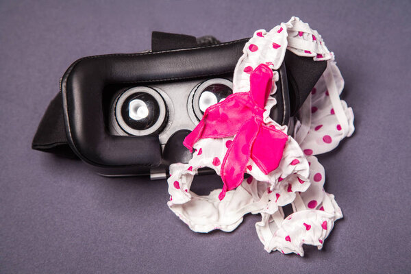 Virtual reality glasses for mobile devices with dotted pink white lingerie with bow on top, vr technology used for porn vr video in adult entertainment.