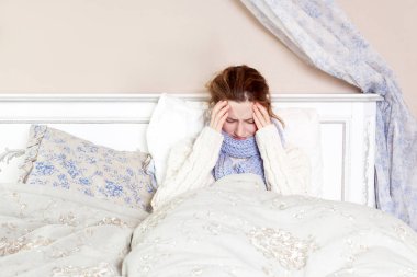 Grip veya soğuk. Mavi eşarp ve yatakta yatarken korkunç baş ağrısı acı ile sinir bozucu genç kadın portre üstten görünüm görüntüsü.