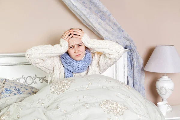 Flu or cold. Closeup top view image of frustrated young woman with blue scarf and suffering from terrible headache while lying in bed. — Stock Photo, Image