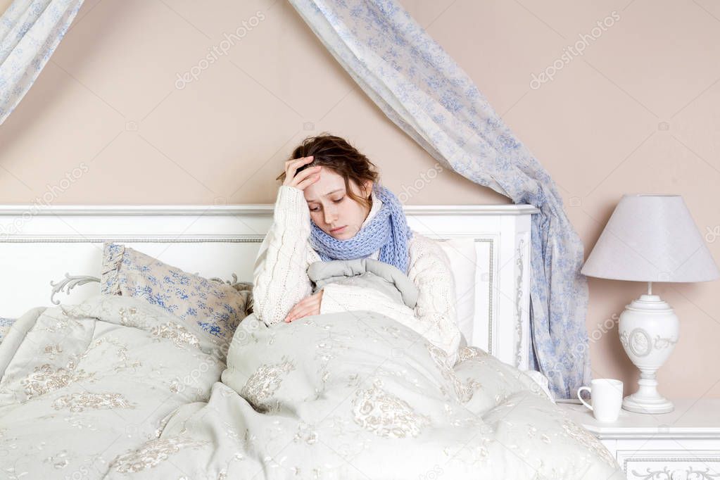 Flu or cold. Closeup top view image of frustrated young woman with blue scarf and suffering from terrible headache while lying in bed.