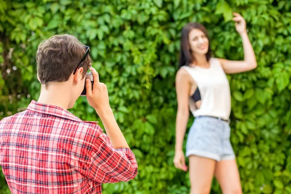 Fotograaf schieten van mooie brunette model in de buurt van de groene muur. — Stockfoto
