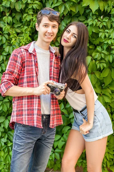 Feliz hermosa pareja cerca de la pared verde en estilo casual con cámara . — Foto de Stock