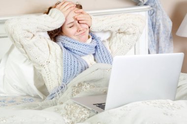 Hasta bir kadın duygu kötü, dinlenme ve onu dizüstü bilgisayar ve internet ile onun yatağında evde çalışma. 