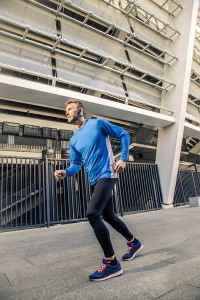 Красивый мужчина средних лет в синей черной спортивной форме бегает . — стоковое фото