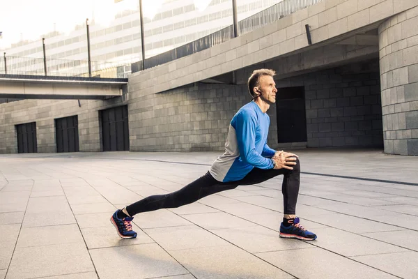 Knappe atleet man in zwart blauw sport uniform lichaam uitrekken — Stockfoto