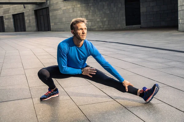 Knappe atleet man in zwart blauw sport uniform lichaam uitrekken — Stockfoto