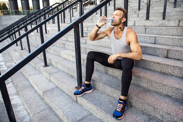 Dorst sportman nemen een rust- en drinkbaar water na het lopen. — Stockfoto