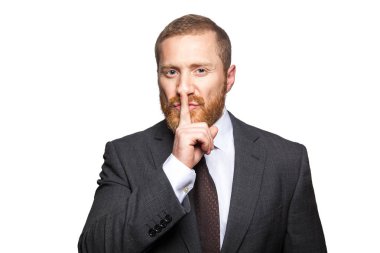 Sessizlik jest yapma dudaklarında parmak ile ciddi iş adamı. Sus!!! Kameraya bakarak beyaz zemin üzerine izole.