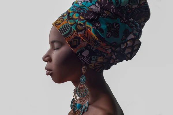 Mladá krásná Afričanka v tradičním stylu s šálou, náušnice pláč, izolované na šedém pozadí. rasismus, deprese nebo osamělost koncepce — Stock fotografie