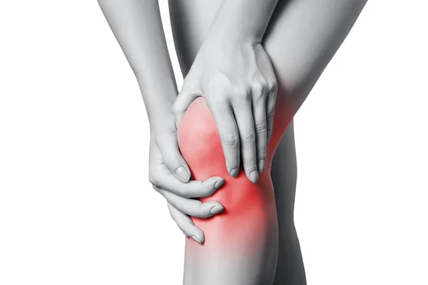 Detailní pohled na mladou ženu s bolestí kolena. izolované na bílém pozadí. Černobílá fotografie s červenou tečkou. — Stock fotografie