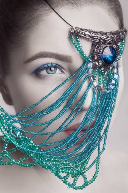 Güzel esmer moda model beyaz yüz cilt rengi ve mavi makyaj ve kırmızı dudakları ile gözü önünde mavi takı portresi. Kameraya bakarak vurdu, stüdyo.