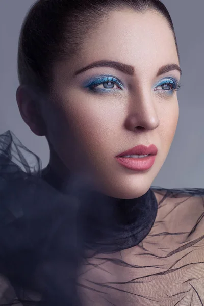 Portrét krásné bruneta modelka s černým závojem a modrý make-up na stříbrné černé mezi. — Stock fotografie