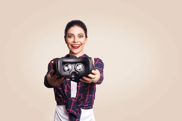 Mujer hermosa joven en estilo casual con auriculares de realidad virtual sobre fondo beige . — Foto de Stock