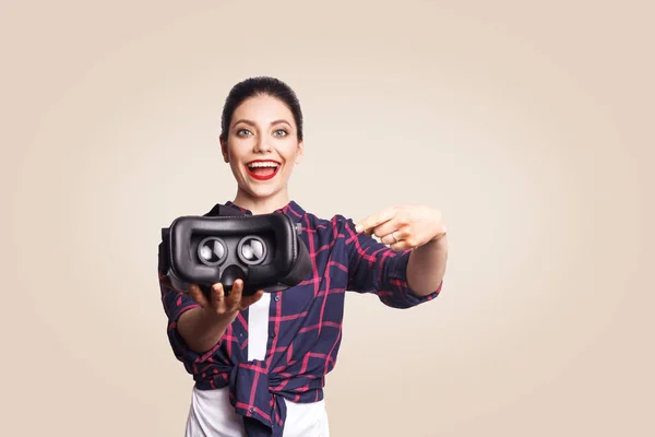 Jovem mulher bonita em estilo casual com fone de ouvido realidade virtual em fundo bege . — Fotografia de Stock