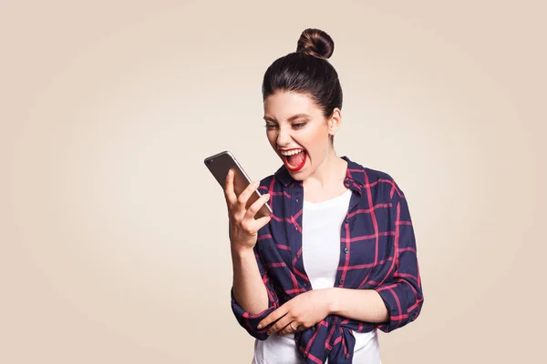 Jovem mulher bonita em estilo casual gritando no telefone. estúdio filmado em fundo bege . — Fotografia de Stock