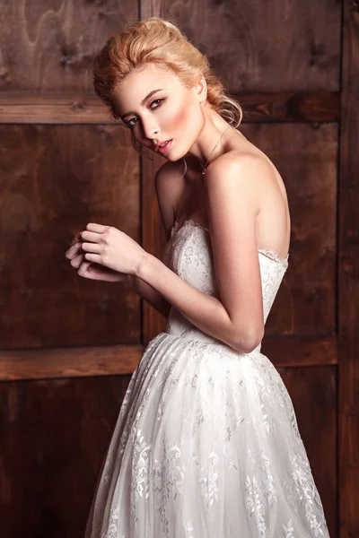 Moda beleza tiroteio nupcial. Bela noiva moda em vestido de noiva posando na frente de fundo amadeirado . — Fotografia de Stock