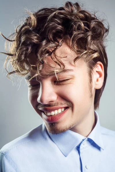 Portrett av en ung mann med krøllete frisyre. Et filmopptak. toothy smil og lukkede øyne . – stockfoto