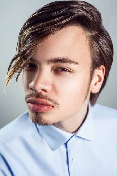 Retrato de jovem com longo penteado franja em seus olhos. Tiro de estúdio. a olhar para a câmara . — Fotografia de Stock