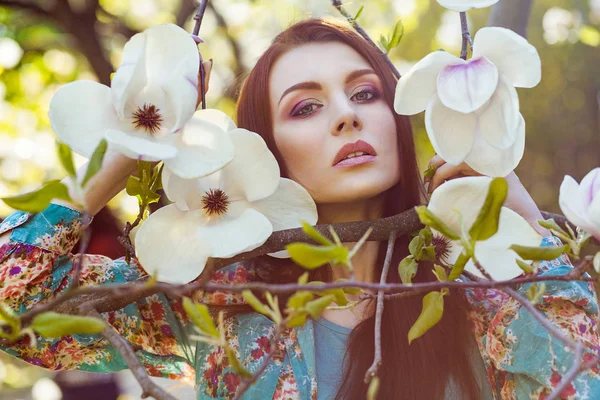 Retrato de jovem bela mulher posando entre árvores florescentes com sombra rosa . — Fotografia de Stock