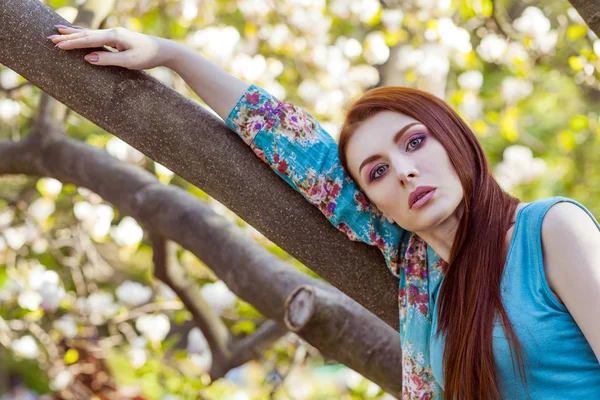 Ritratto di giovane bella donna in posa tra alberi in fiore con ombretto rosa . — Foto Stock