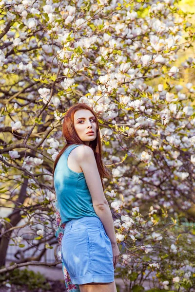 Ritratto di giovane bella donna in posa tra alberi in fiore con ombretto rosa . — Foto Stock