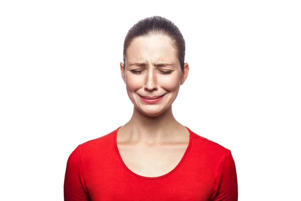 Portrait of sad unhappy crying woman in red t-shirt with freckles. closed eyes, studio shot. isolated on white background. — Stock Photo, Image