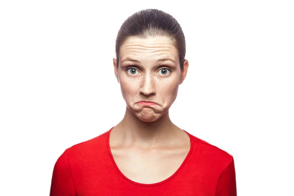 Ich weiß es nicht. Porträt einer lustigen verwirrten Frau in rotem T-Shirt mit Sommersprossen. Blick auf Kamera, Studioaufnahme. isoliert auf weißem Hintergrund. — Stockfoto