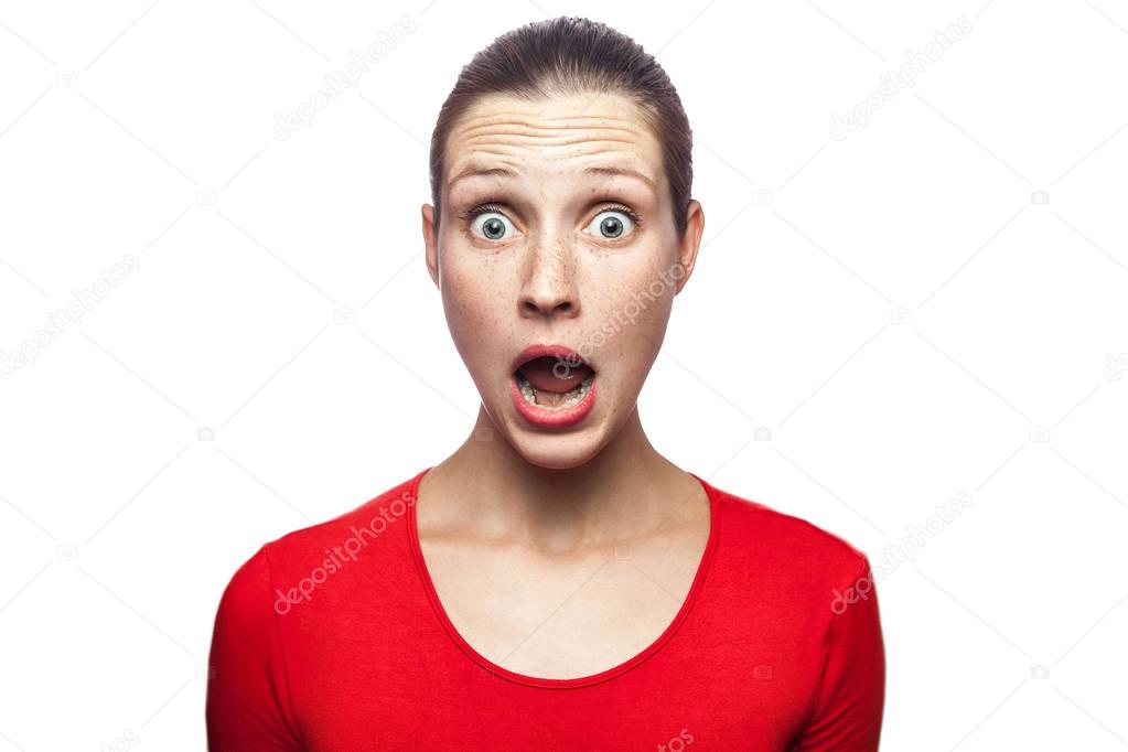 Portrait of happy surprised woman in red t-shirt with freckles. looking at camera excited with big eyes, studio shot. isolated on white background. 