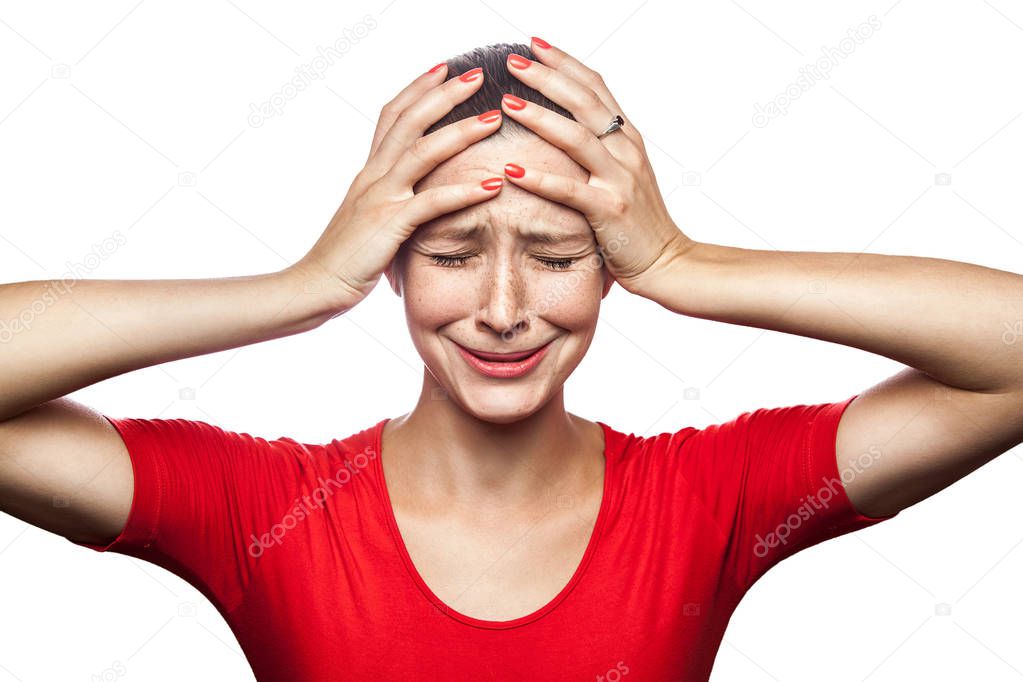 Portrait of sad unhappy crying woman in red t-shirt with freckles. closed eyes hands on head, studio shot. isolated on white background. 