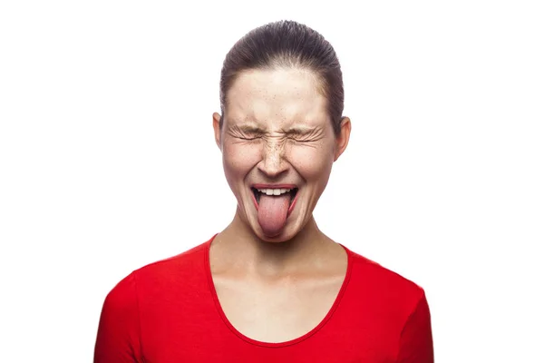 Retrato de una loca mujer divertida en camiseta roja con pecas y lengua. ojos cerrados, filmación de estudio. aislado sobre fondo blanco . — Foto de Stock